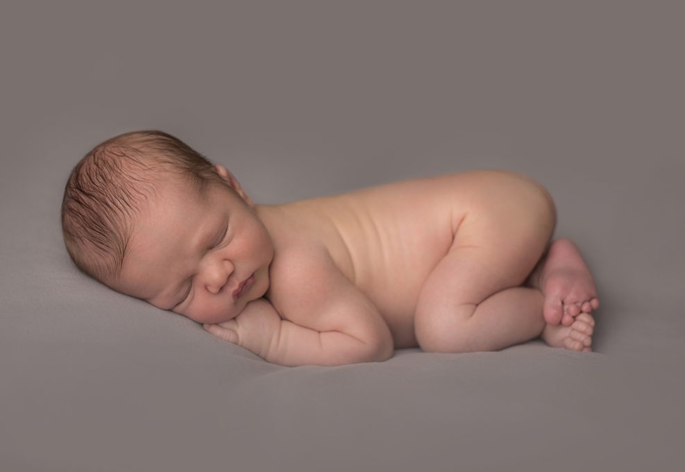 Nouveau-né posé sur un fond beige pour séance naissance par Bellules et compagnie photographe en Auvergne Rhone-Alpes