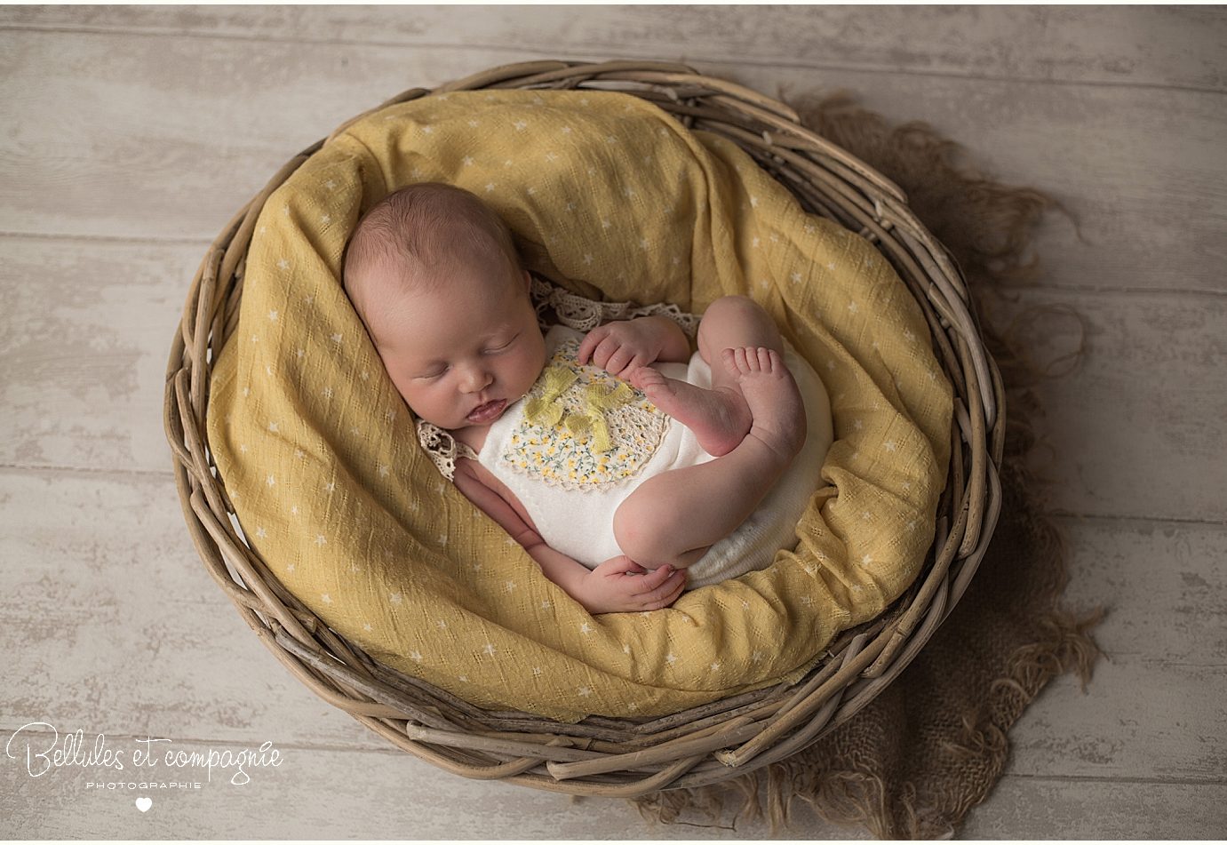 Nourrisson dans un panier et accessoires jaune en séance naissance par photographe Bellules et Compagnie Clermont-Ferrand