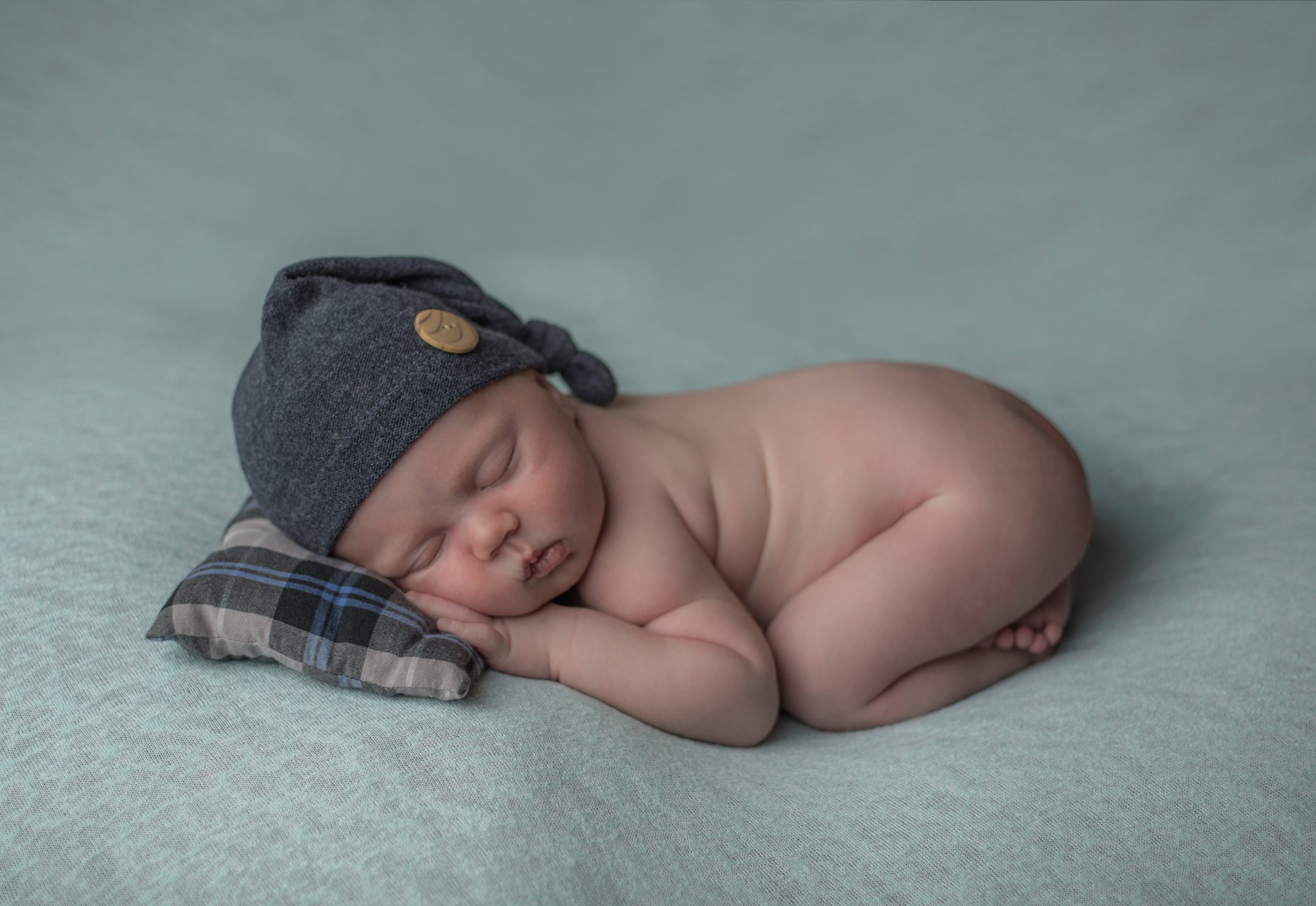 Nourrisson sur fond vert avec bonnet par bellules et compagnie photographe naissance clermont-ferrand